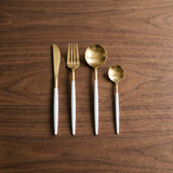 France Set — gold and white flatware on a warm wood table
