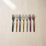 Milan Fruit Fork — jewel-toned fruit forks on a warm wood table