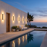 Cascade Wall Light mounted on a pool house wall, reflected in the water at dusk