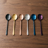 Paris Spoon — jewel-toned dinner spoons on a warm wood table