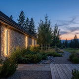 Stripe Lined Wall Lights mounted on a garden wall above planting at dusk