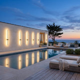 Luminous Line Outdoor Lights on a pool house wall, reflected in the water at dusk
