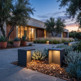 Block Lane Outdoor Solar Light glowing among garden planting at dusk