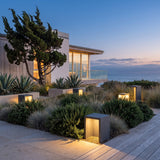 Block Lane Outdoor Solar Light set among garden planting at dusk