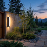 Cascade Wall Light mounted on a garden wall above planting at dusk